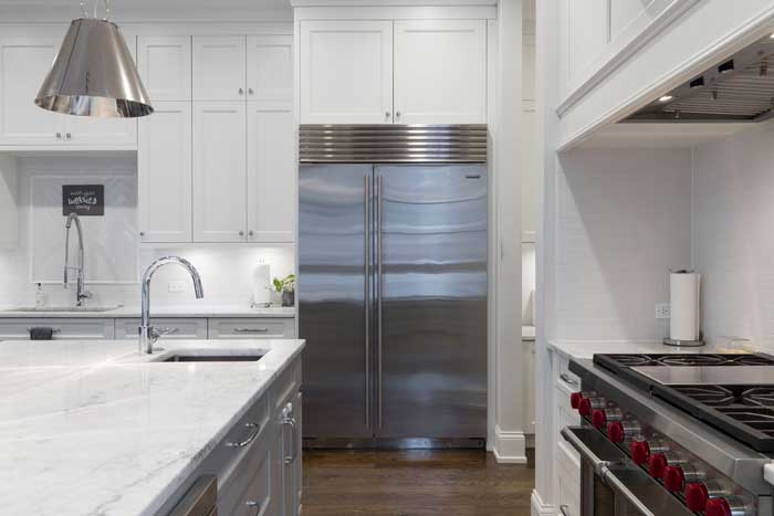 A white kitchen with a side-by-side type refrigerator