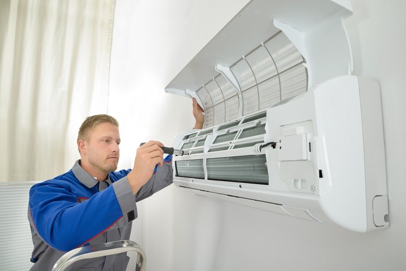 A man cleaning the air conditioner coils.