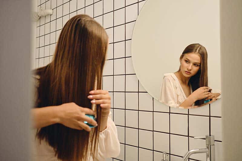 woman brushing hair in bathroom