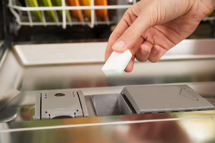 A person putting salt on their dishwasher