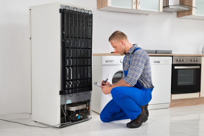 Male Technician checking the back of a refrigerator