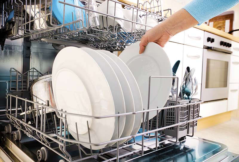 A person loading dishes into a dishwasher