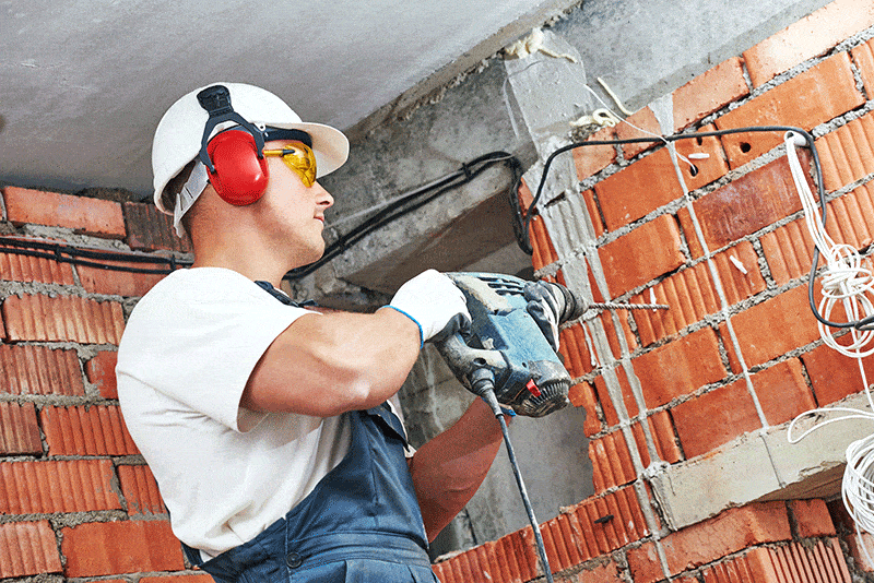A corded drill being used on a brick wall