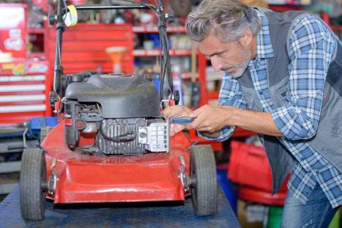 male fixing a lawn mower on a table