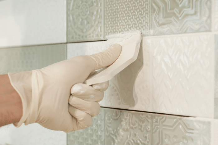 Male putting grout in between tiles