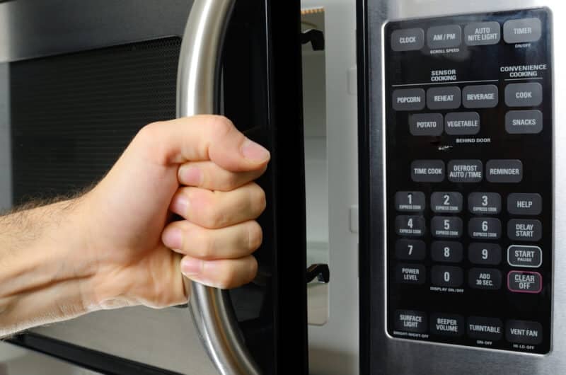 A person opening a microwave door