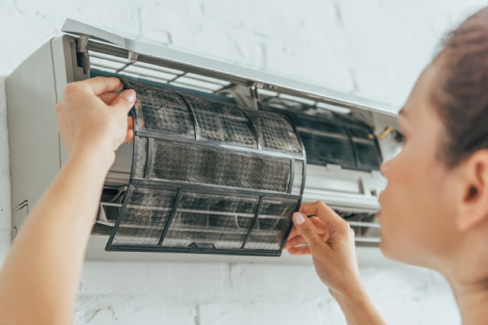 female checking the air filter of AC