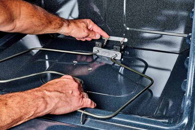 Man hands replacing an electric oven bake element