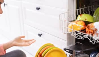Woman looking angry at her broken dishwasher