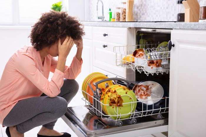 Worried woman about his dishwasher because the dishes don't come out clean