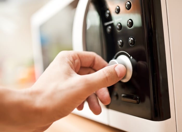 A person adjusting the dials on a microwave