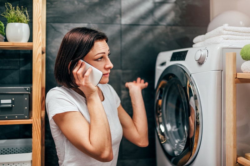 Worried woman calling a professional to fix her dryer