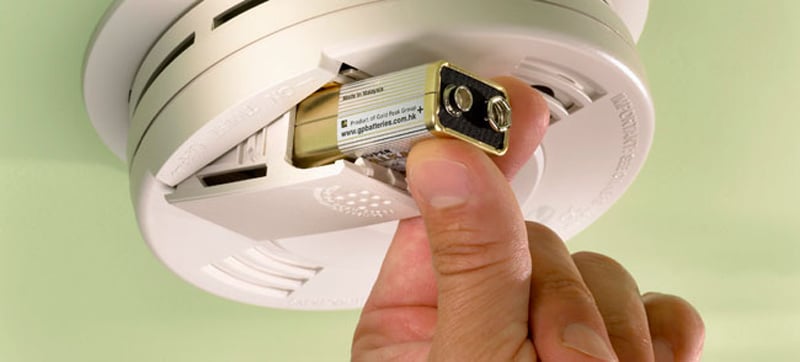 Hand changing battery of a smoke alarm