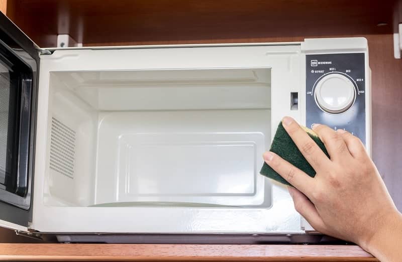 A hand cleaning the microwave