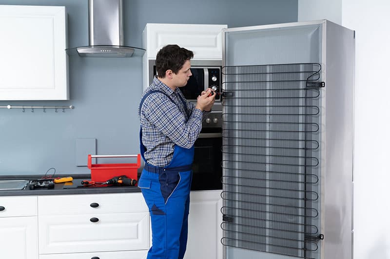 man fixing condenser coils of a refrigerator