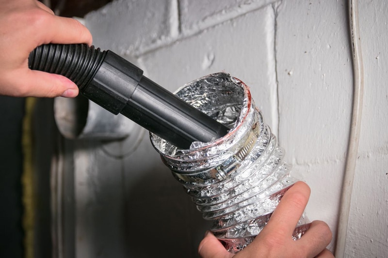 Cleaning the dryer vent duct with a vacuum.
