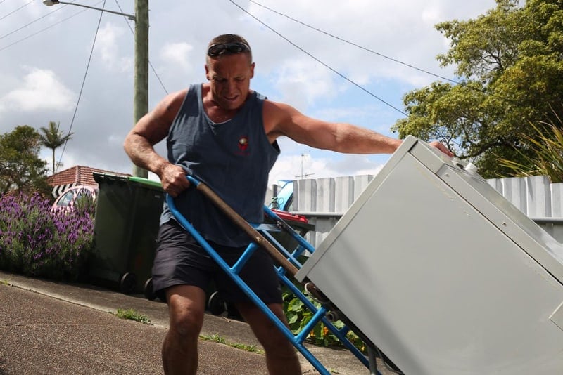 Man moving a dishwasher with a wheelbarrow