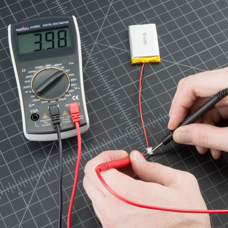 Hands using a multimeter with a battery