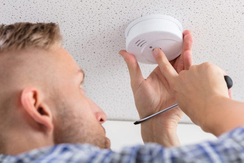 Man pressing button on smoke alarm