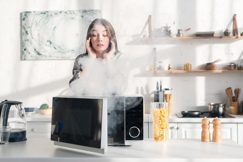 A woman shocked by the steam coming out of the microwave