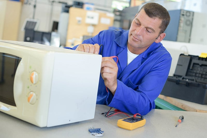 man testing the microwave with a multimeter