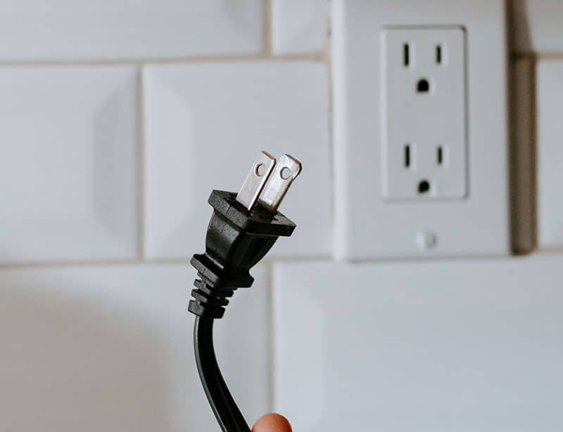 A plug with a wall outlet in the background