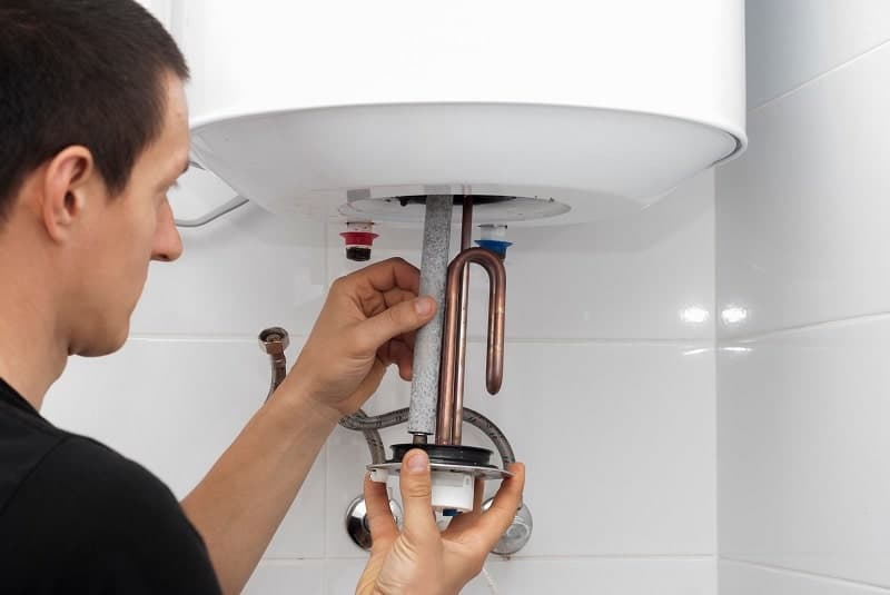 A man checking the water heater's heating element