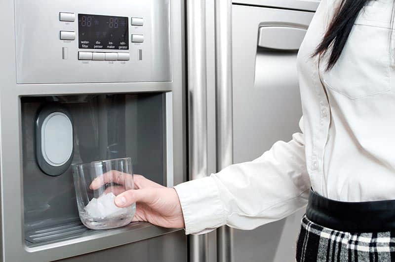 A woman getting ice from a refrigerator