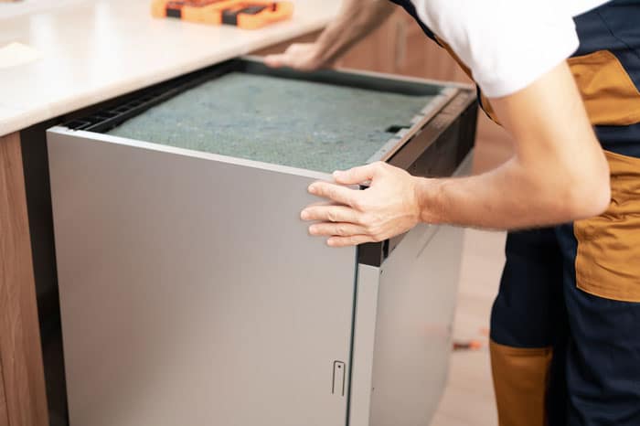 man removing dishwasher from a kitchen countertop