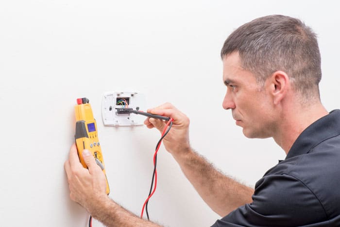 male rewiring the thermostat