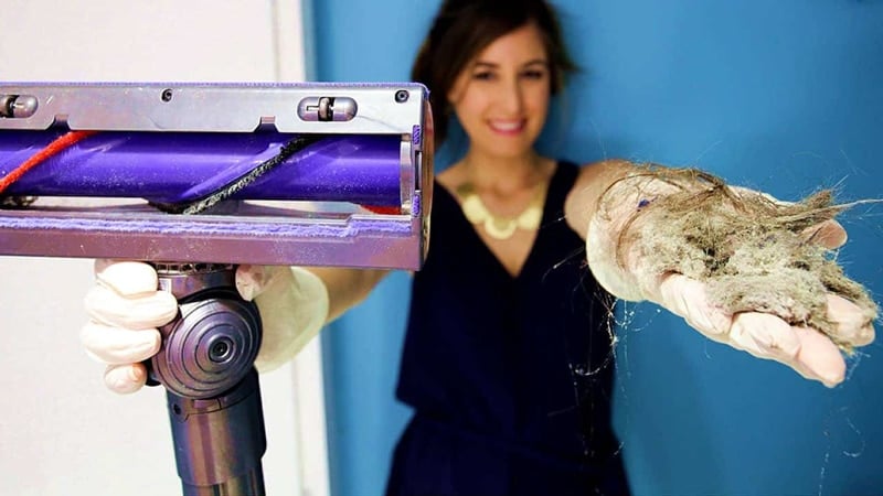 Woman holding a vacuum in one hand and lint in the other