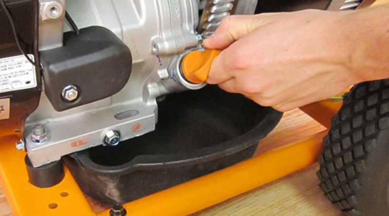 A person removing a generator's oil plug.