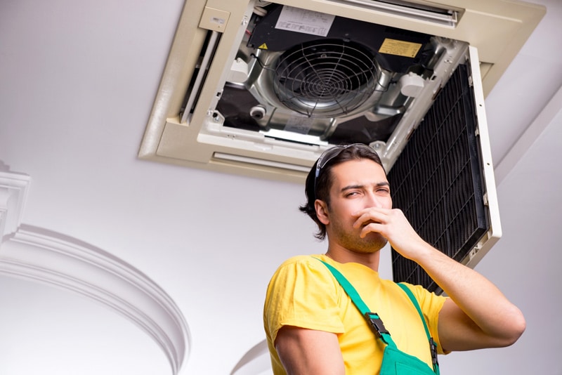 Technician fixing smelly air conditioner