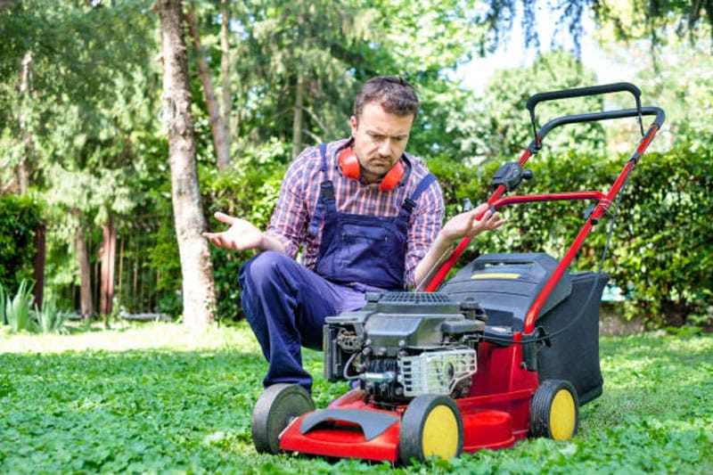 Man beside his not working lawn mower