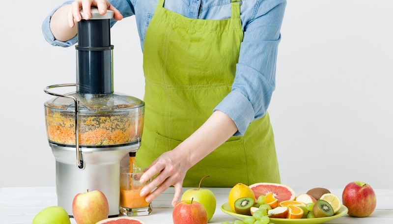 Woman with apron preparing a healthy fruit juice