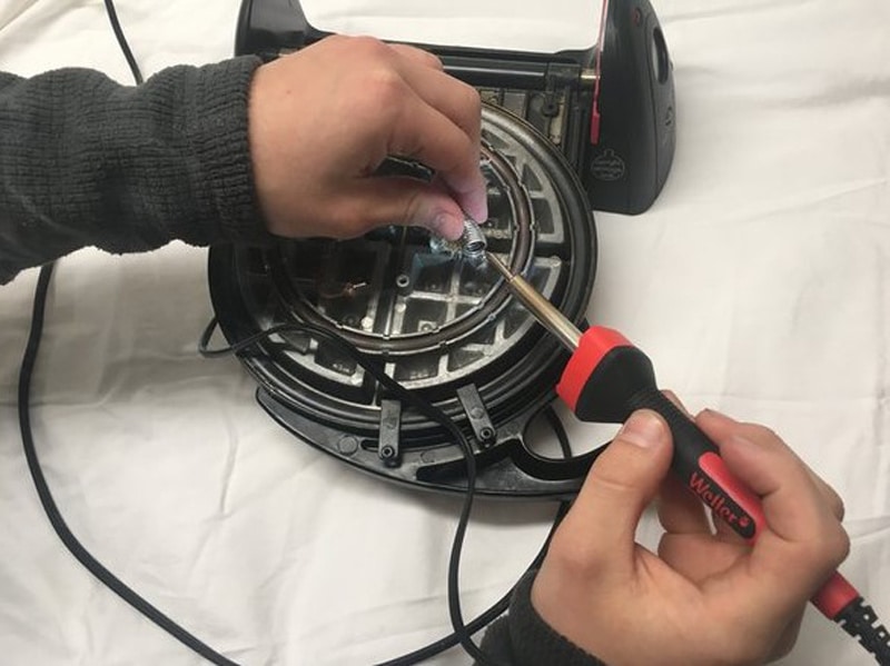 Man Using a Soldering to fix waffle iron
