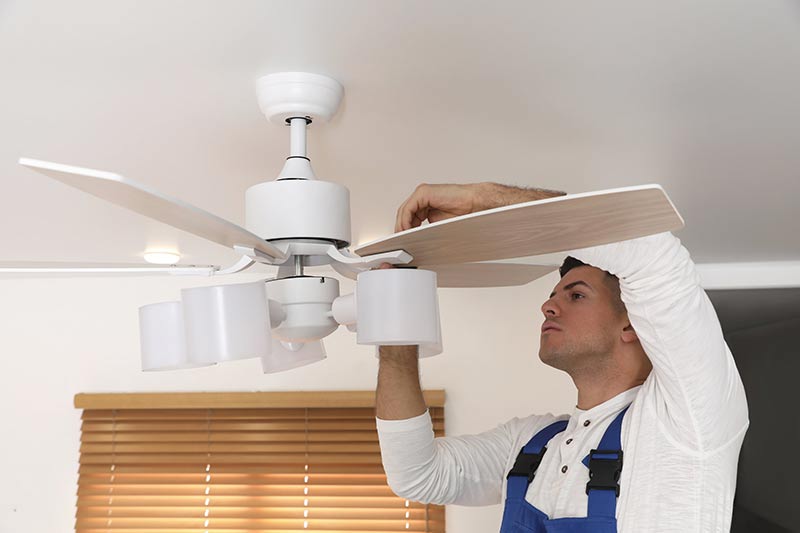 a repair man fixing the ceiling fan blades