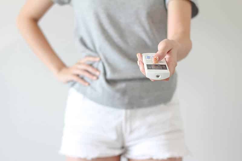 A person holding a ceiling fan remote