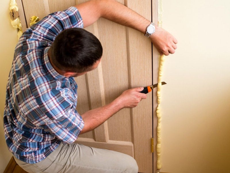 Man cutting off excess door insulation