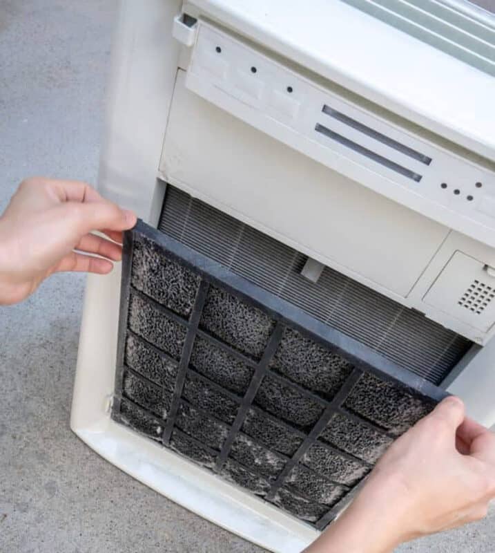 Hands taking out air purifier filter to clean it