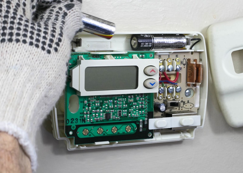 Hand Replacing Thermostat Batteries