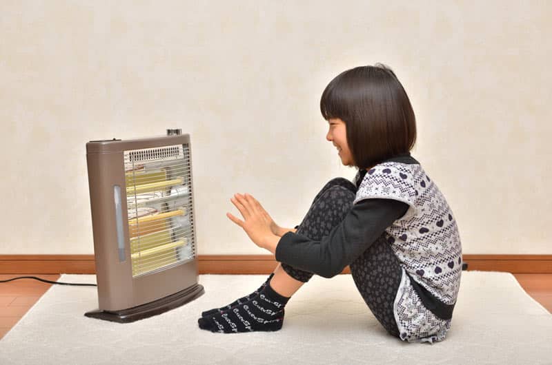 Girl warming up by a heater