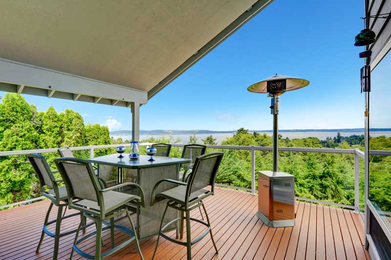 outdoor patio with chairs, tables and patio heater overlooking scenic view