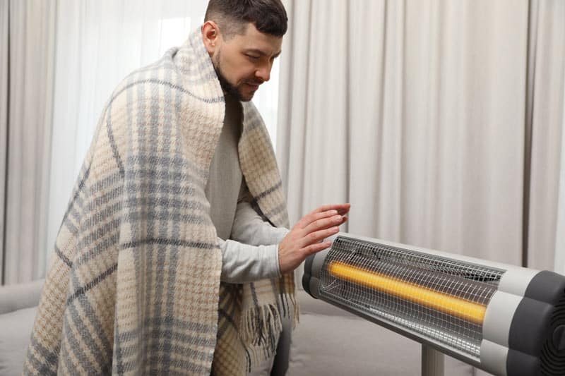 man warming up hands in front of infrared heater