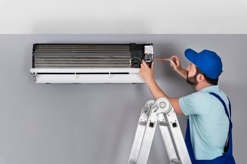Man Using Ladder To Disconnect Air Conditioner