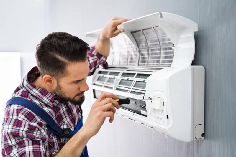 Repairman Using Screwdiver To Fix Air Conditioner