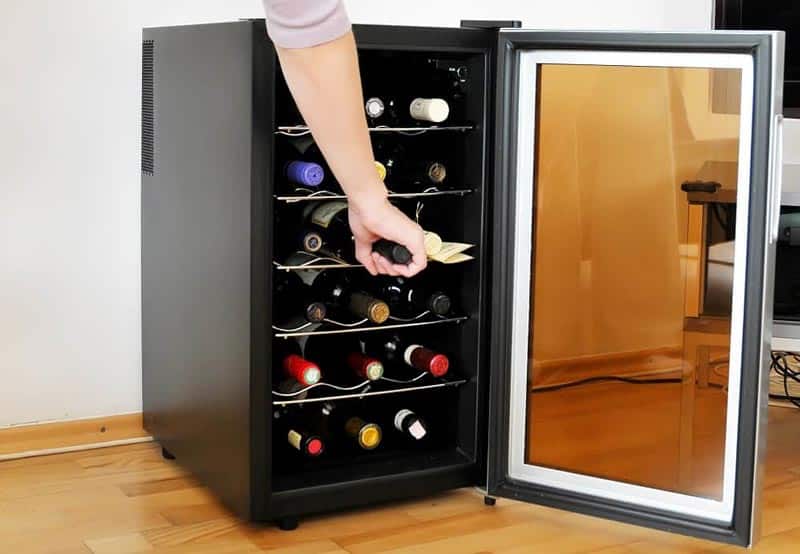 Hand Removing One Bottle Of Wine From Wine Cooler