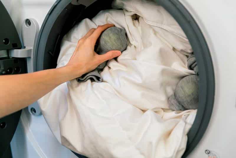 Hand Putting Clothes Inside Washer