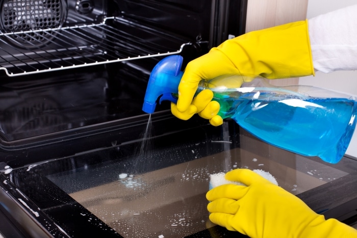 A person cleaning an oven glass door