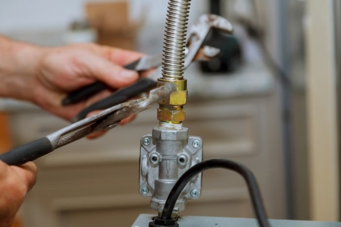 A person tightening an oven gas line